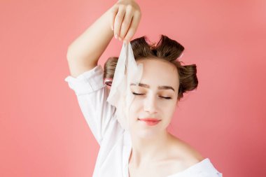 Yüzüne dokunmadan bir maske ve curlers ile güzel genç kız.