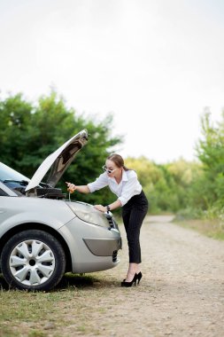 Arabası bozulduktan sonra yol kenarındaki genç kadın hasarı görmek için kaputu açtı.