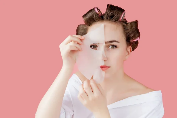 Mooi jong meisje met een masker en krulspelden die haar gezicht aanraken. — Stockfoto