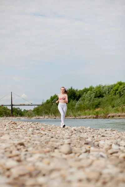 Το κορίτσι που τρέχει στην όχθη του ποταμού. Υγιής γυναίκα γυμναστικής τζόκινγκ σε εξωτερικούς χώρους. — Φωτογραφία Αρχείου
