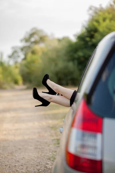 Primo piano di piedi con scarpe nere sui tacchi alti di ragazza attraente. Lei sta mettendo le gambe attraverso la finestra del trasporto moderno . — Foto Stock