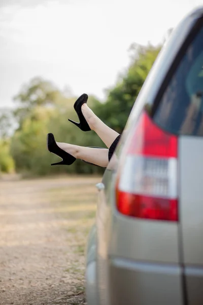 Крупним планом ноги з чорним взуттям на високих підборах привабливої дівчини. Вона прокладає ноги крізь вікно сучасного транспорту . — стокове фото