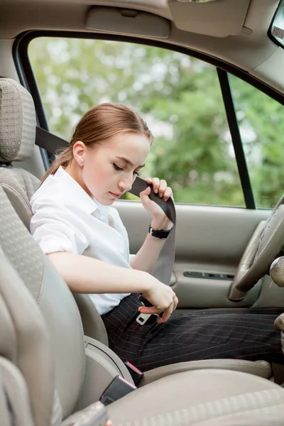 Жіноча рука застібає ремінь безпеки автомобіля. Закрийте ремінь безпеки вашого автомобіля, сидячи всередині автомобіля перед водінням і здійснивши безпечну подорож. Крупним планом знімок жіночого водія кріпиться ремінь безпеки — стокове фото