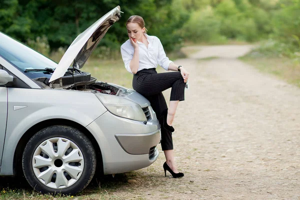 彼女の車が故障した後、道端で若い女性彼女は被害を見るためにフードを開いた — ストック写真