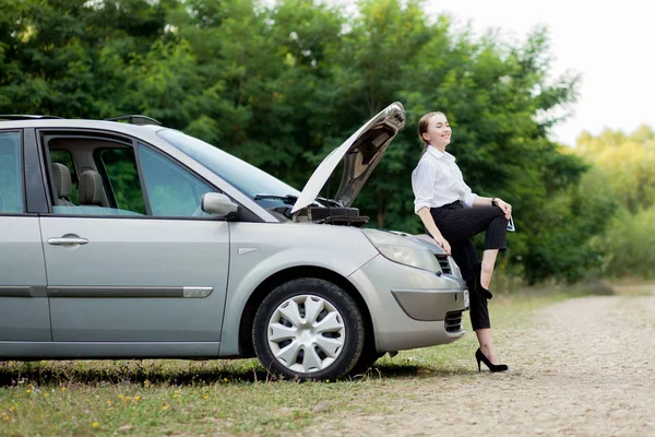 Молода жінка біля узбіччя після того, як її машина зламалася Вона відкрила капот, щоб побачити пошкодження — стокове фото