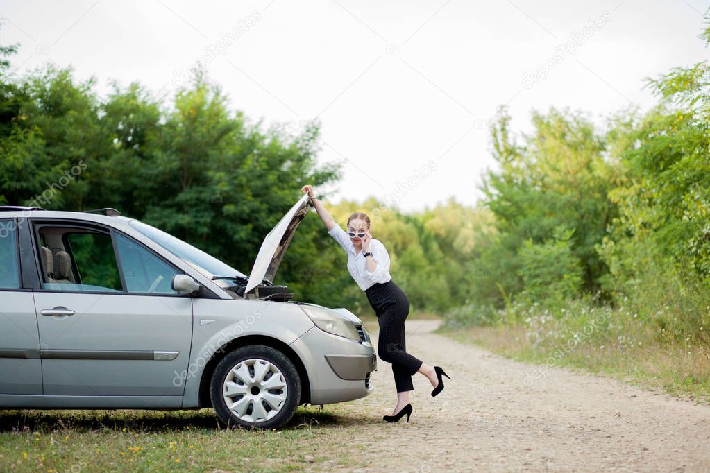 Young woman by the roadside after her car has broken down She opened the hood to see the damage