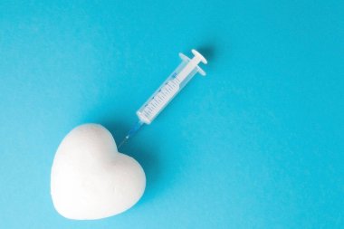 Mavi Kağıt arka planda bir şırınga ile beyaz kalp şekli CL