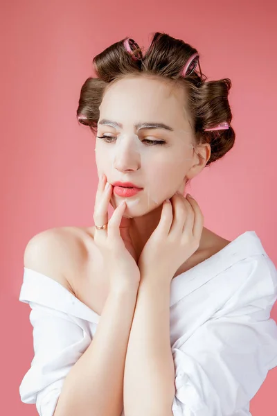 Menina bonita com uma máscara e curlers tocando seu rosto . — Fotografia de Stock