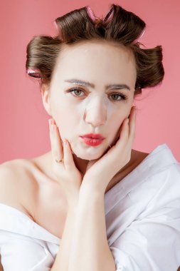 Yüzüne dokunmadan bir maske ve curlers ile güzel genç kız.