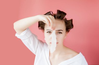 Yüzüne dokunmadan bir maske ve curlers ile güzel genç kız.