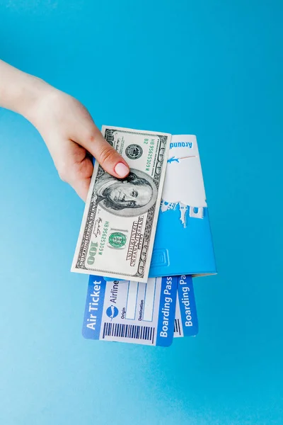Passaporte, dólares e bilhete de avião na mão de mulher em um fundo azul. Conceito de viagem, espaço de cópia — Fotografia de Stock