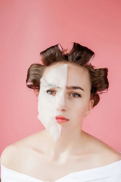 Mooi jong meisje met een masker en krulspelden die haar gezicht aanraken. — Stockfoto