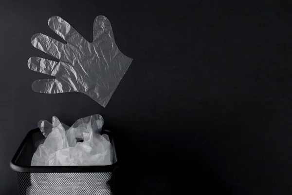 Plastikowa torba z uchwytami, rękawice w pojemniku na czarnym oświetlenie tła — Zdjęcie stockowe