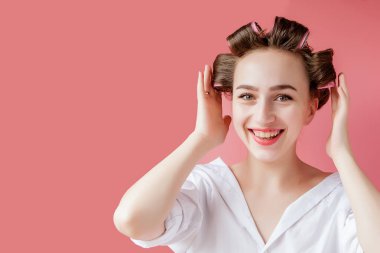 Pembe arka planda saç bigudili güzel bir kız.