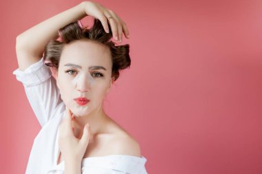 Yüzüne dokunmadan bir maske ve curlers ile güzel genç kız.