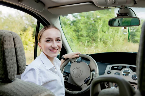 Close up portrait of pleasant looking female with glad positive expression, being satisfied with unforgettable journey by car, sits on driver s seat. People, driving, transport concept