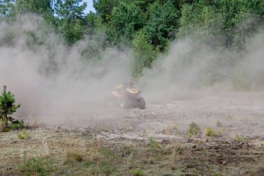 Sarı dörtlü Atv'ye binen adam kumlu bir ormanda tüm arazi aracına biniyor. Ekstrem spor hareketi, macera, turistik.