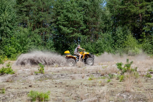 Az ember egy sárga quad ATV quadozás minden terepjáróval a homokos — Stock Fotó