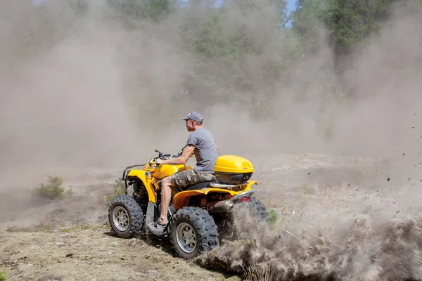 Man riding a yellow quad ATV all terrain vehicle on a sandy fore — Stock Photo, Image