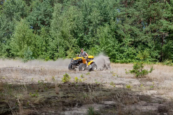 Man riding a yellow quad ATV all terrain vehicle on a sandy fore — Stock Photo, Image
