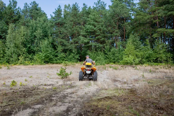 Homme conduisant un quad jaune VTT tout terrain sur un front sablonneux — Photo