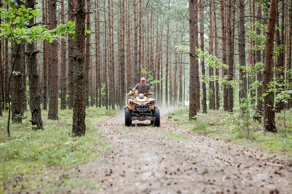 Uomo a cavallo di un quad giallo ATV tutti i veicoli terreno su una foresta sabbiosa. Sport estremi moto, avventura, attrazione turistica . — Foto Stock