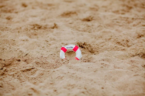 Primer plano de boya salvavidas en miniatura excavado en la arena en la playa — Foto de Stock