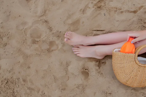 Girl oil spray tanning her legs protection from the sun\'s uv rays putting sunscreen lotion sunblock Unrecognizable girl with her beach essentials for a summer holiday.