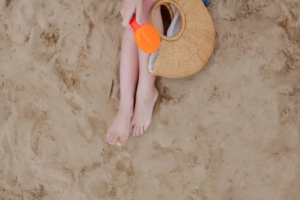 Κορίτσι λάδι σπρέι μαυρίσματος της προστασίας των ποδιών από τις ακτίνες UV του ήλιου βάζοντας αντηλιακή λοσιόν αντιηλιακό μη αναγνωρίσιμο κορίτσι με την παραλία της βασικά για μια καλοκαιρινή διακοπές. — Φωτογραφία Αρχείου