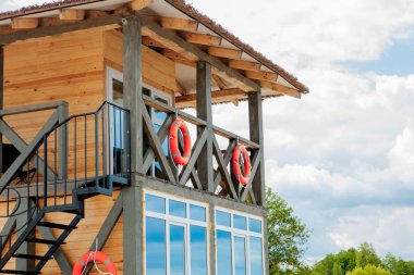 Sahilde kurtarma baywatch için Cankurtaran kulesi. Bulutlu gökyüzü arka plan üzerinde deniz kıyısında ahşap ev. Yaz tatili ve tatil köyü. Kamu koruma ve güvenlik konsepti