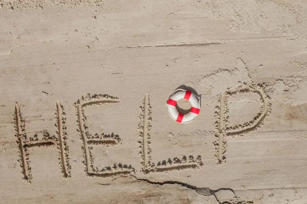 Ayúdame con la inscripción y la boya salvavidas en la arena. Por favor ayúdame. En una playa tropical — Foto de Stock