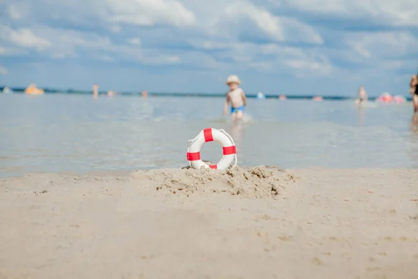 Primer plano de Lifebuoy en la playa sobre fondo de bebé. Seguridad en el agua . — Foto de Stock