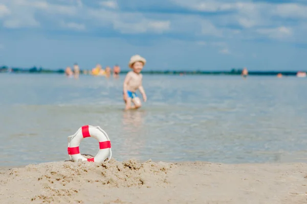 Primer plano de Lifebuoy en la playa sobre fondo de bebé. Seguridad en el agua . — Foto de Stock
