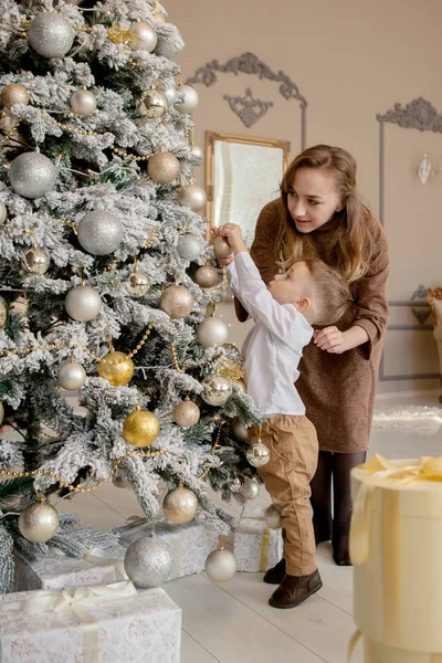 Mãe e seu pequeno filho decorando árvore de Natal com brinquedos e guirlandas — Fotografia de Stock