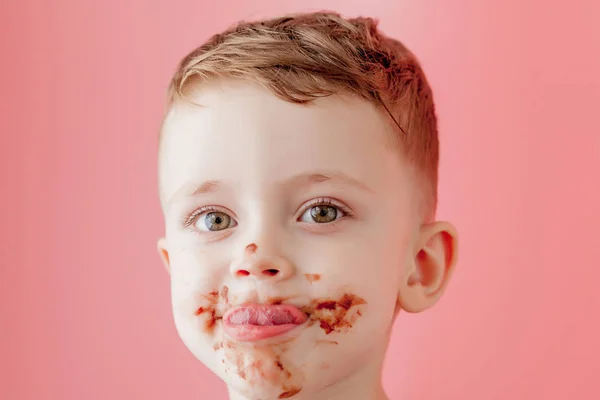 Мальчик ест шоколад. Милый счастливый мальчик, намазанный шоколадом вокруг рта. Концепция ребенка . — стоковое фото