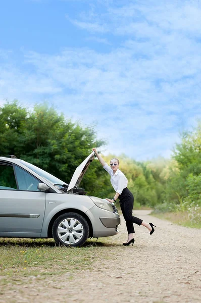 Joven mujer al borde de la carretera después de que su coche se ha roto Ella abrió la capucha para ver el daño —  Fotos de Stock