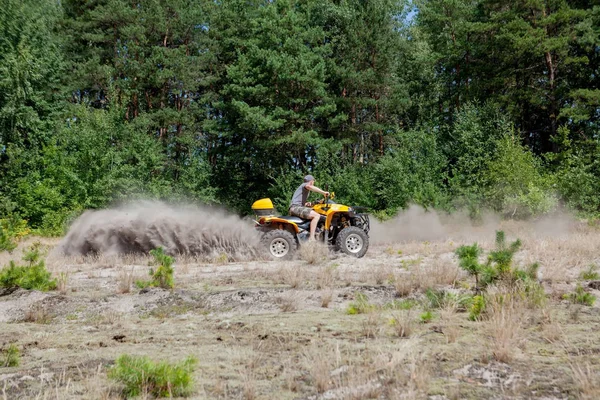 Az ember lovaglás egy sárga quad ATV minden terepjáróval a homokos erdőben. Extrém sport mozgás, kaland, turistalátványosság. — Stock Fotó