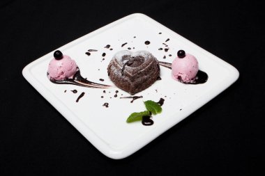 Tatlı fondan çikolata siyah bir zemin üzerine beyaz bir plaka üzerinde dondurma ile. Enfes Fransız çikolata tatlı fondan, metin için yer