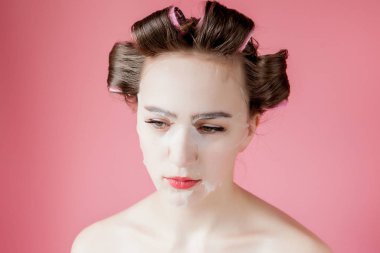 Yüzüne dokunmadan bir maske ve curlers ile güzel genç kız.