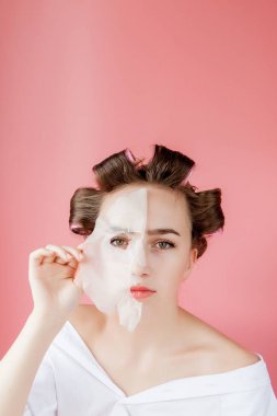 Yüzüne dokunmadan bir maske ve curlers ile güzel genç kız.