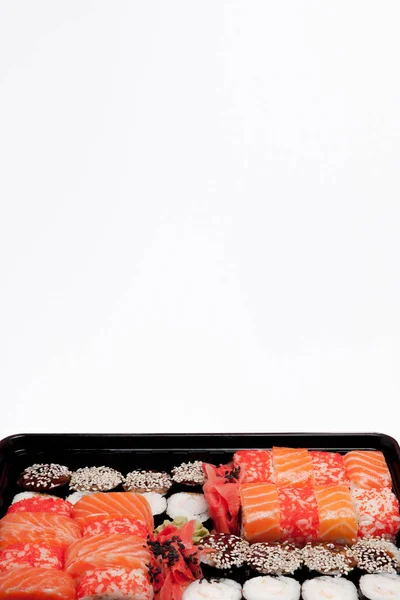 Big sushi set ib black plastic box on white background, top view