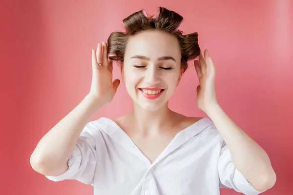 Menina bonita em encrespadores de cabelo no fundo rosa — Fotografia de Stock