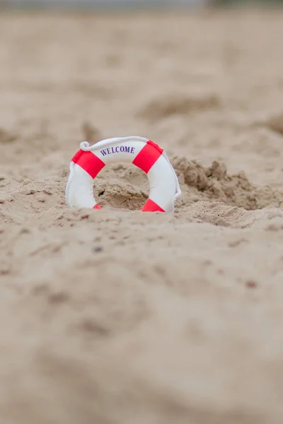 Nahaufnahme von Miniatur-Rettungsring, der sich am Strand in den Sand gräbt — Stockfoto