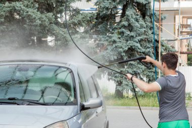 Bir adam yaz outdoo bir self-servis lavabo da arabasını yıkar