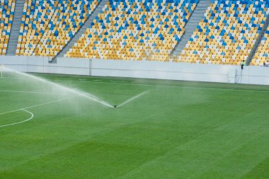 Stadyumda otomatik çim çim sulama sistemi. Bir futbol topu,