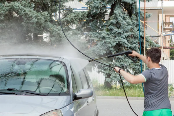 Bir adam yaz outdoo bir self-servis lavabo da arabasını yıkar