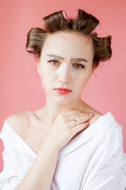 Yüzüne dokunmadan bir maske ve curlers ile güzel genç kız.