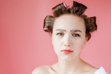 Yüzüne dokunmadan bir maske ve curlers ile güzel genç kız.