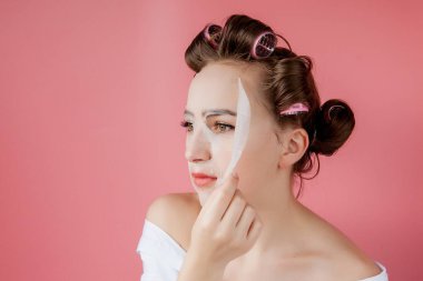 Yüzüne dokunmadan bir maske ve curlers ile güzel genç kız.