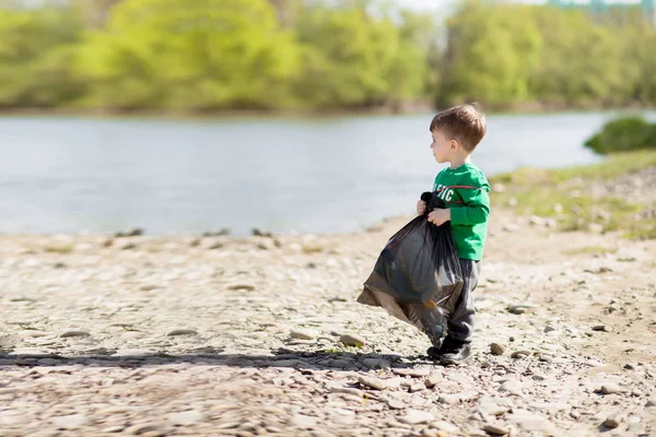 Αποθήκευση έννοια περιβάλλον, ένα μικρό αγόρι μαζεύοντας σκουπίδια και PL — Φωτογραφία Αρχείου